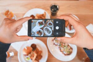料理の写真をスマートフォンで撮影する人